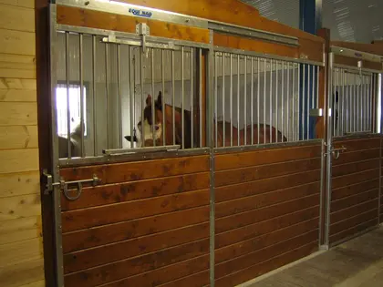 Façade de box pour chevaux avec remplissage en bois et barreaux métalliques.